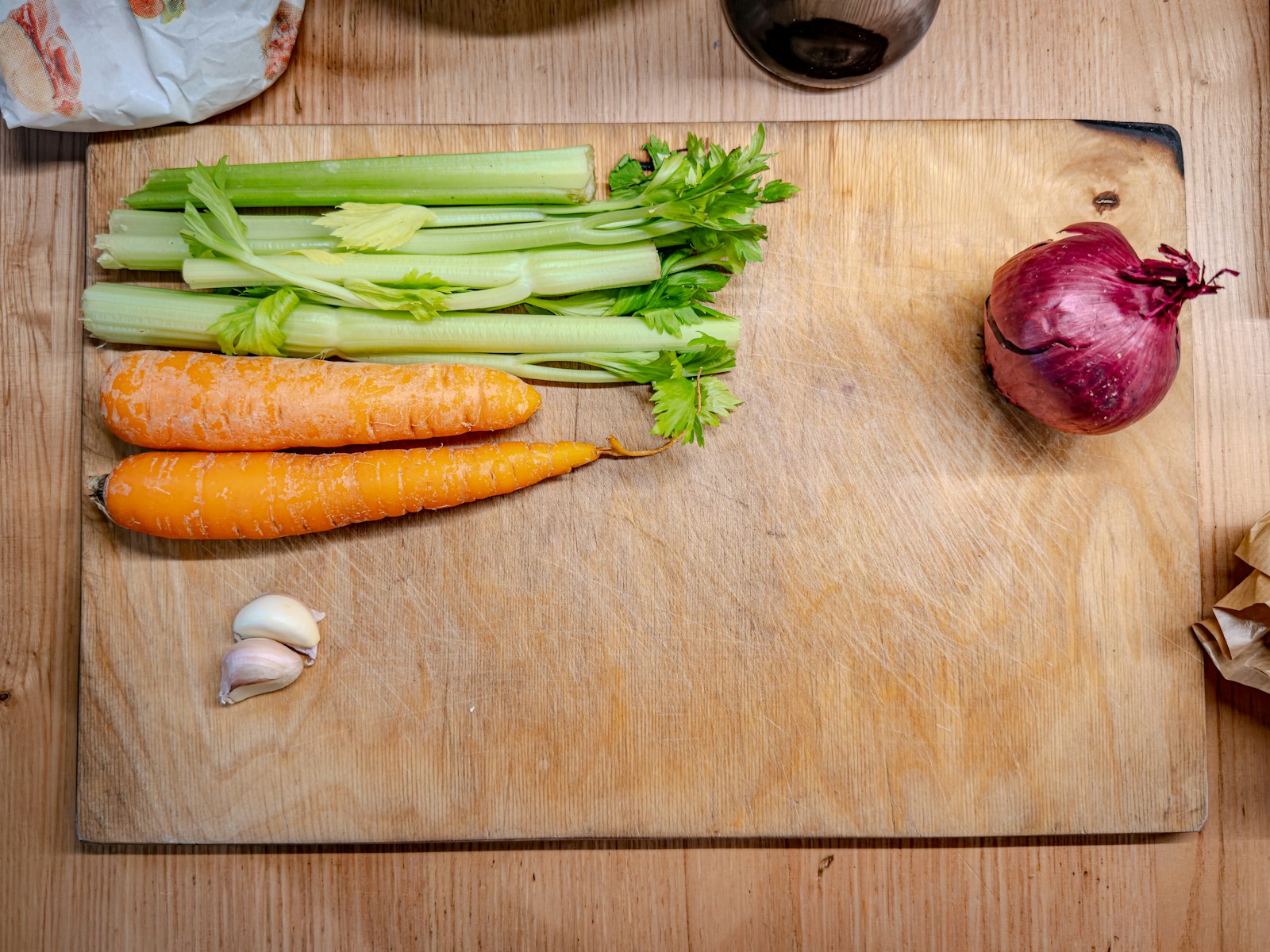Fresh carrots, celery, onion and garlic on a wooden chopping board
